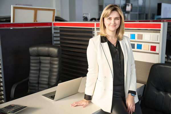 Девушка стоит рядом со столом продавца автомобилей в салоне продаж