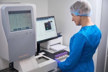 Kadın laboratuvar asistanı veri tabanına girer, laboratuvarda modern ekipmanlar vardır.