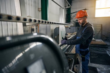 Erkek, yüksek teknolojili ekipmanlarda camın kenarını inceliyor. Koruyucu eldiven takan bir adam.