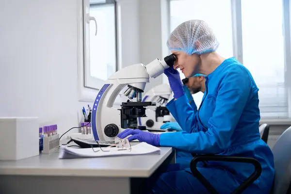 Female Virologist Examines Biological Material Microscope Her Colleague Works Nearby — Stock Photo, Image