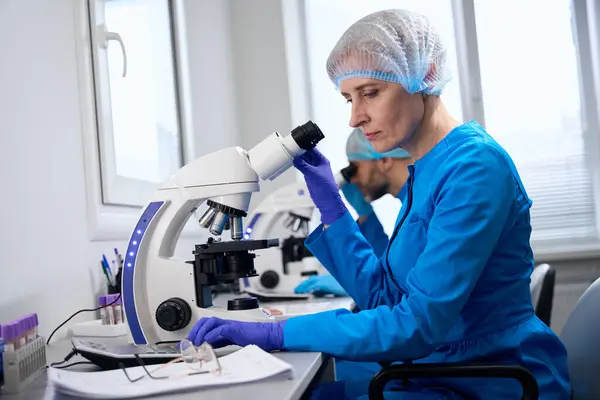 Female Laboratory Assistant Examines Biological Material Microscope While Her Colleague — Stock Photo, Image