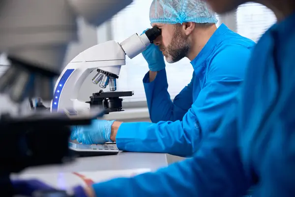 Middle Aged Male Uses Powerful Microscope While His Colleague Working — Stock Photo, Image