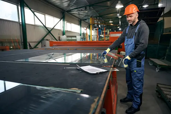 Master cuts glass for a double-glazed window, modern high-tech equipment is used in production