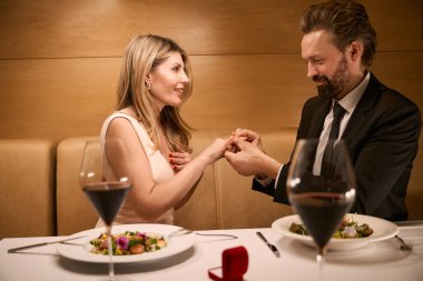 Adam yoldaşlarının parmağına yüzük takıyor. Bir çift restoranda romantik bir akşam yemeği yiyor.