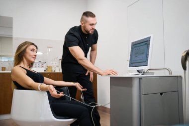 Fizyoterapist doktor teşhis için bileklerine elektrot takmış. İnsanlar sağlık merkezinde.