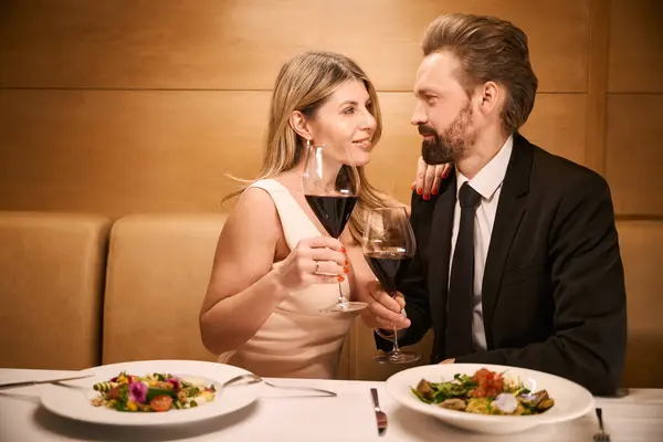 Middle-aged lady and her companion are talking over a romantic dinner in a restaurant, the lady has a deep neckline