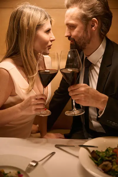 Middle-aged couple in a restaurant with glasses of red wine, the lady has a deep neckline