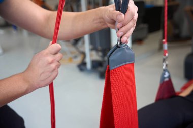 Rehabilitasyon terapisti Redcord kullanan bir kadın hastayla modern ekipmanlar kullanarak çalışıyor.
