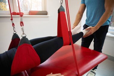 Kadın, kırmızı kablodaki askıya alınmış bir döngü sistemine bağlanmış durumda. Modern bir iyileştirme tekniği kullanılıyor.