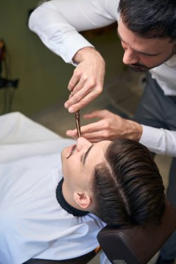 Hippi müşteri bıyığını şekillendirmek için berber dükkanını ziyaret ediyor.