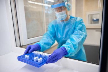 Koruyucu ekipman laboratuvar asistanı elinde deney tüpleriyle bir laboratuvar düzenleyicisi tutuyor.