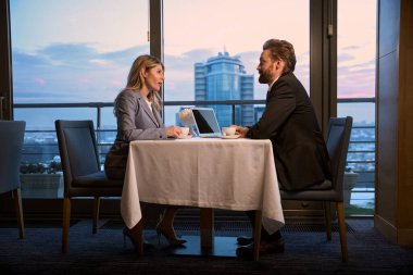 İş kadını iş ortağıyla kahve içerken iletişim kuruyor.