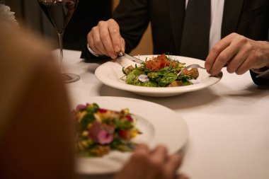 Sıcak bir restoranda yemek yiyen çift, hafif salata servis ediliyor.
