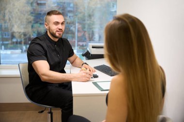 Uzman bir sağlık merkezinde resepsiyon düzenliyor, insanlar parlak bir ofiste oturuyorlar.
