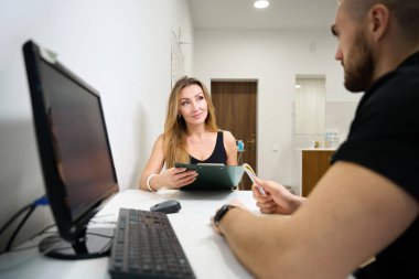 Kadın fizyoterapist randevusunda, hasta bir anket doldurur.