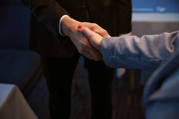 Female with a neat manicure and a male shake hands, they are in elegant business suits