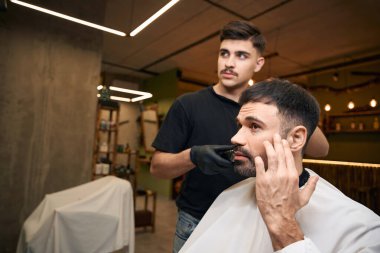 Profesyonel kuaför berber dükkanında saç makasıyla müşteriye saç kesimi yapıyor.