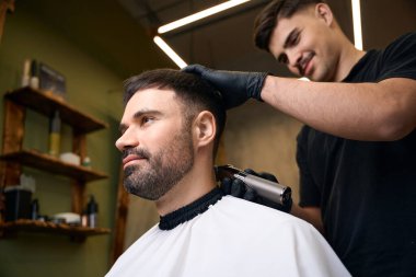 Yakışıklı sakallı adam berbere yeni saç stili yaptırıyor.