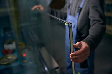 Bir pencere yapımında çalışan işçiler, uzay aracı çerçevesinin ilk mührünü taşır. Takım elbiseli bir adam.