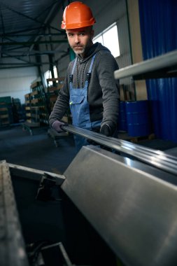 Orta yaşlı işçiler, turuncu kasklı bir adam olan pencere yapımında teknolojik bir işlem gerçekleştiriyor.