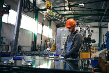 İşçi cam ile çalışmak için özel aletler kullanır, güvenlik kaskı takan bir işçi.