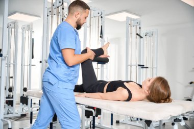 Rehabilitasyon merkezinde kadın hastayla çalışan fizyoterapist, rahat egzersiz kıyafeti giyen kadın.