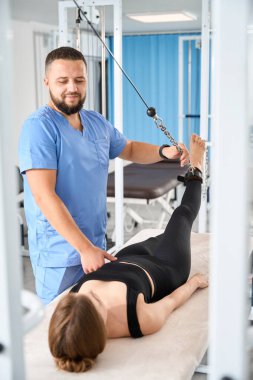 Rehabilitasyon merkezinde çalışan hasta masaj masasında yatarken özel bir simülatör kullanır.