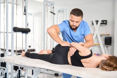 Osteopat genç bir kadının omurgası ile çalışır, hasta masaj masasında bulunur.