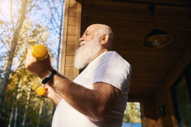 Sağlıklı emekliler sabah egzersizlerini dambıllarla yapar, temiz havada egzersiz yapar.