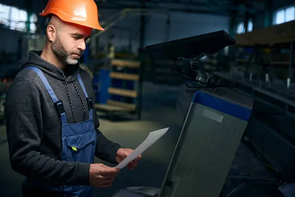 Employee works with production documentation at the workplace, high-tech equipment is used in production