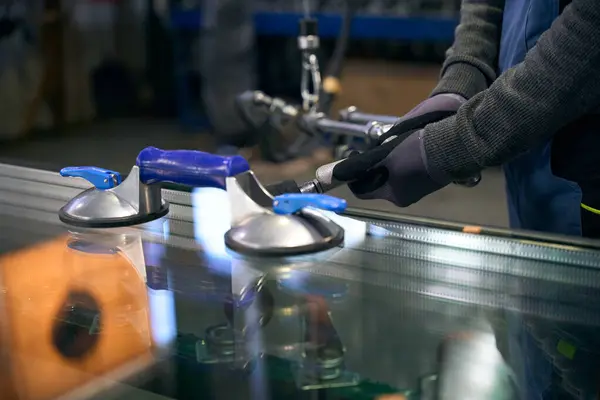 Technological process of pressing a double-glazed window, a person works in protective gloves