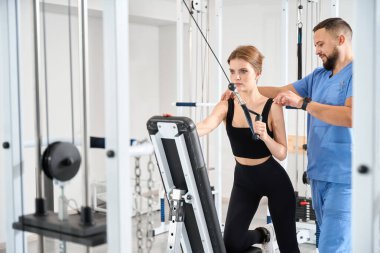 Üniformalı doktor hastayla özel bir simülatörde çalışıyor. Kliniğin modern ekipmanları var.