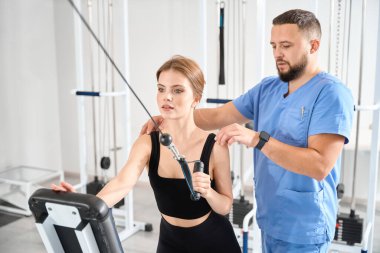 Doktor bir hastayla özel bir simülatörde çalışıyor. Kliniğin modern ekipmanları var.