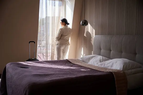 Baksidan Kvinnlig Tittar Genom Gardinfönstret Hennes Hotellrum Stockbild