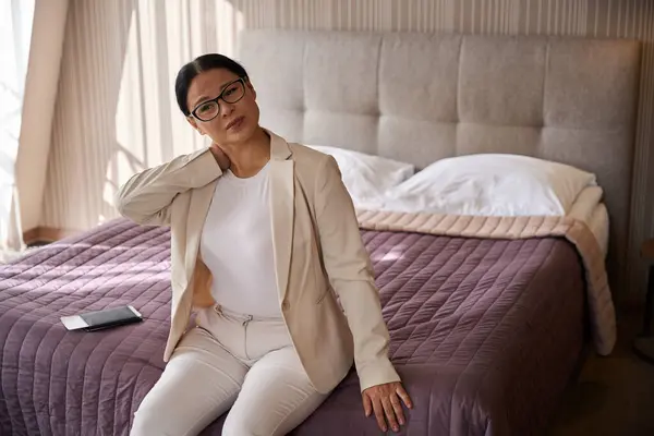 Traurige Geschäftsfrau Mit Nackenschmerzen Sitzt Auf Bettkante Ihrer Suite Stockfoto