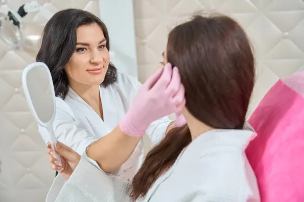 Patientin Sitzt Stuhl Mit Spiegel Der Hand Während Dermatologe Ihre Stockbild