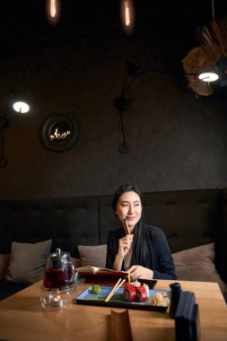 Gülümseyen yaratıcı kadın, Asya mutfağında rahat bir restoranda oturuyor ve düşüncelerini defterine yazıyor. Genç yazar, anılarıyla geleceğin en çok satan kitabı üzerinde çalışıyor.