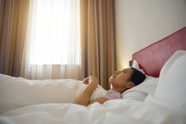 Rüya gibi genç bir kadın, yumuşak beyaz yastığının üzerinde, yorgana sarılmış, yukarı bakıyor.