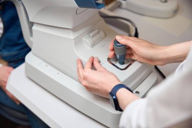 İşyerindeki doktor oftalmolog, özel bir cihaz kuruyor.