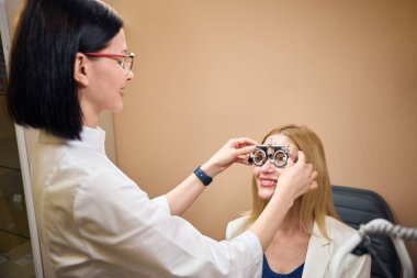 Oftalmolog bir hasta için deney lensleri dener, doktor özel bir cihaz kullanır.