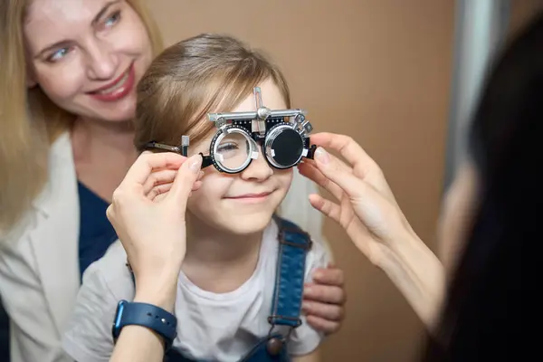 stock image Cute girl with her mother at an appointment with an ophthalmologist, the child is trying on trial lenses