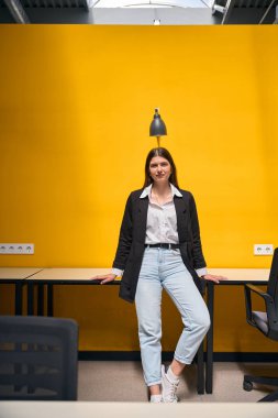 Bir ofis binasında iş yerinin yanında duran genç bayan.