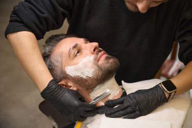 Kendine güvenen profesyonel berber müşterilerinin boynuna tıraş kremi sürüyor ve onu jilet takip ediyor. Erkekleri ipek gibi yumuşak, berber dükkanı servisi bırakıyor.