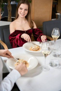 Lüks restoranda yemek yiyen mutlu genç bir bayan, flört eden bir adam. Romantizm, tarih, ilişki kavramı