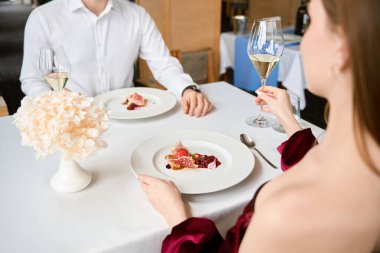 Romantik bir çift, ellerinde beyaz şarapla restoranda oturuyor. Romantizm, tarih, ilişki kavramı