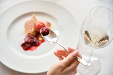 Tatlı yiyen bayana yakın çekim, restoranda kaşık, masada şarap kadehi. Yaşam tarzı, hizmet kavramı