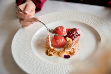 Elinde kaşık olan genç bir kadının restoranda lezzetli bir tatlı yiyeceği yakın plan. Yaşam tarzı, hizmet kavramı