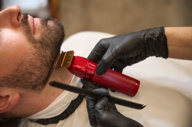 Makro yakın plan yetenekli berber, berber dükkanını düzenli olarak ziyaret eden yakışıklı bir müşterinin yakasının altındaki tüm kılları kesiyor.