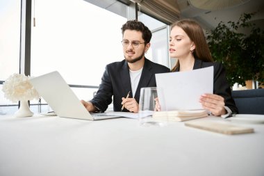 Laptop ve belgelerle çalışan genç bir çift restoranda oturmuş iş görüşmesi yapıyorlar. İş, ortaklık, teknoloji kavramı