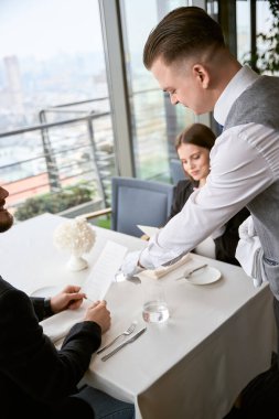 Garson, restoranda yemek siparişi veren bir adama ve kadına yardım ediyor. Romantizm, tarih, ilişki kavramı